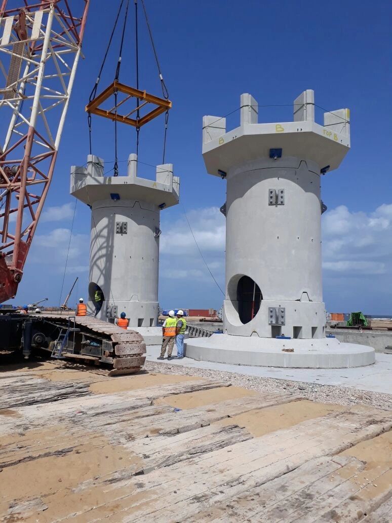 Precast concrete intake structures being set by crane at a waterfront construction site